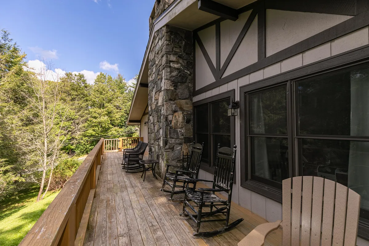 A wooden deck with classic rocking chairs and a sturdy stone wall, overlooking the natural surroundings. The space is calm and perfect for morning coffee, quiet family conversations, or simply enjoying the fresh mountain air at sunrise or sunset.
