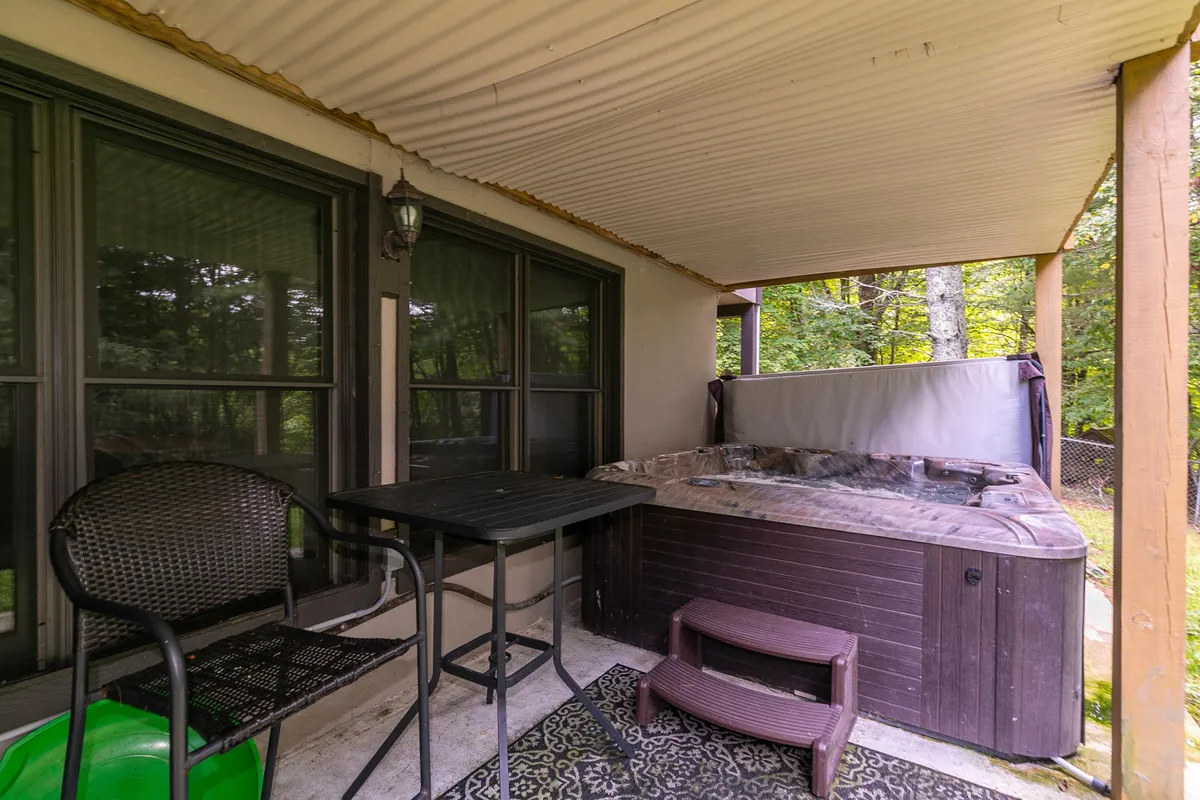 A natural outdoor setting with a bubbling hot tub, an outdoor dining table and chairs, and lush surroundings. The area is inviting, providing a perfect space for relaxing after a day of adventure in the great outdoors.