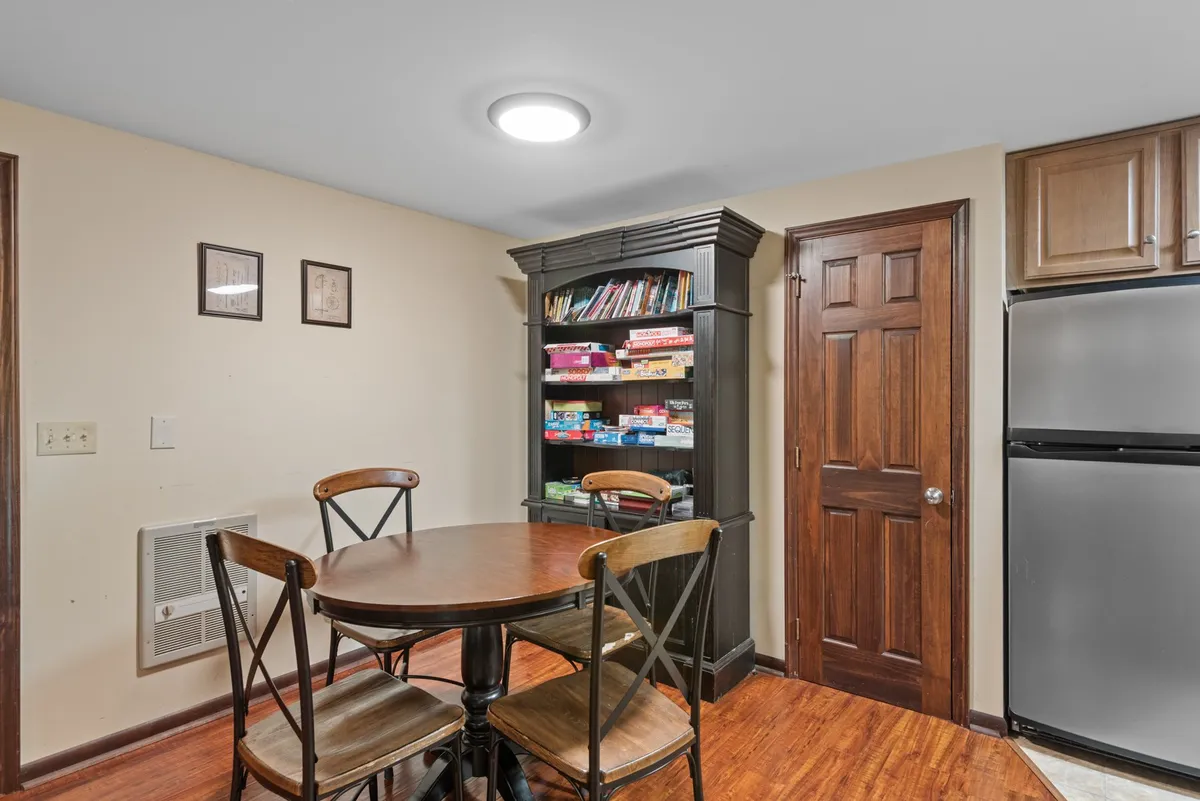 A welcoming dining area featuring a dining table ready for shared meals, a bookshelf that could hold favorite board games, and inviting wall art. The setting is perfect for family dinners, casual gatherings, or lively game nights.