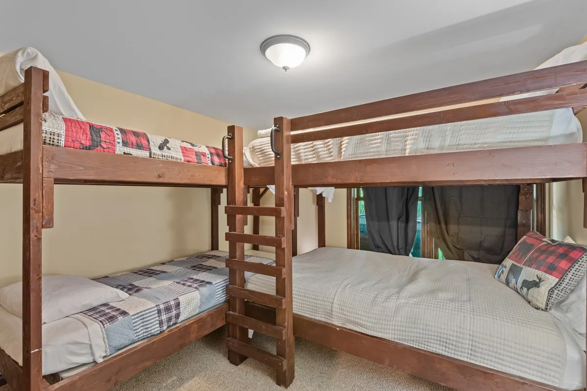 A playful bunk room with full-over-full bunk beds, plaid bedding, and a ladder, designed for group fun and memorable sleepovers. The space is functional yet inviting, tailored for kids or teens.