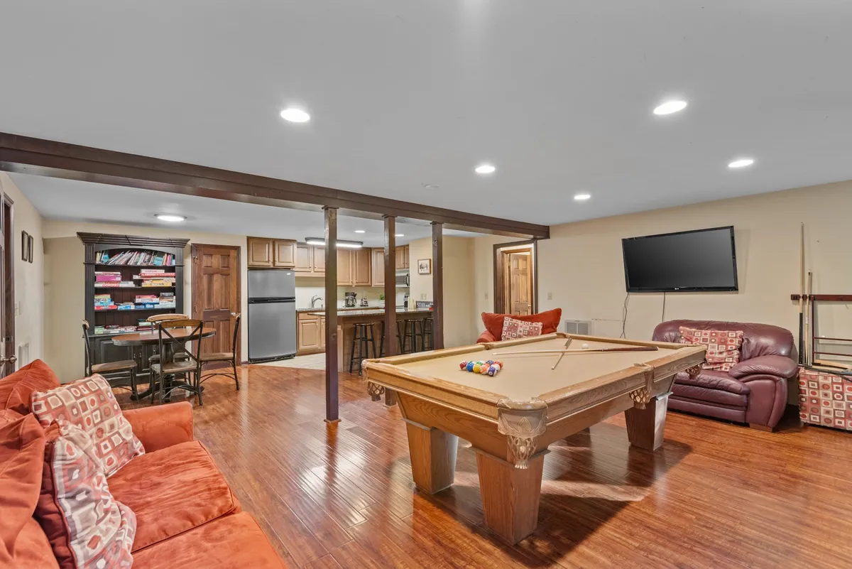 A social recreation space with a pool table, plush sofas, and a view into the kitchen area. The casual layout encourages friendly games and group interaction, echoing the playful, communal aspect of a mountain getaway.